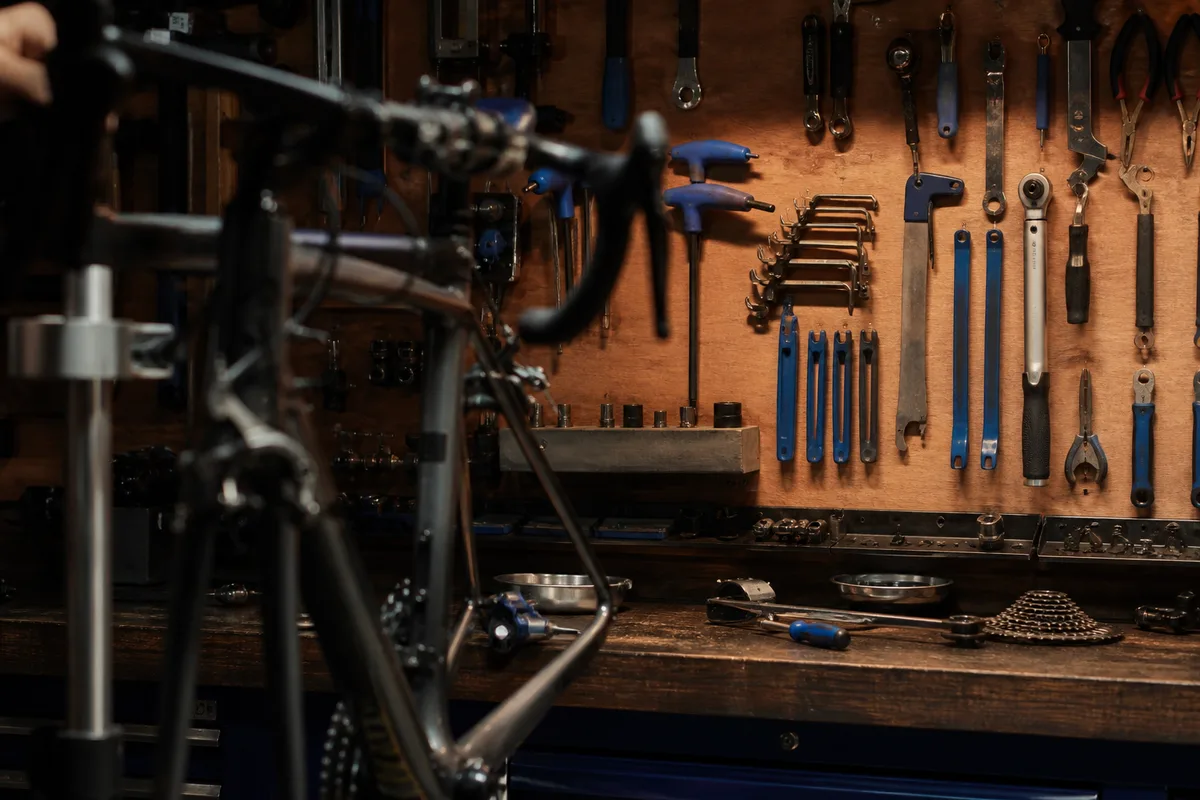 Établi de mécanique cycle avec outils rangés et un vélo maintenu sur un pied d’atelier